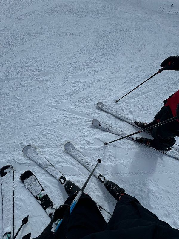 Skiers are preparing to descend a snowy slope.