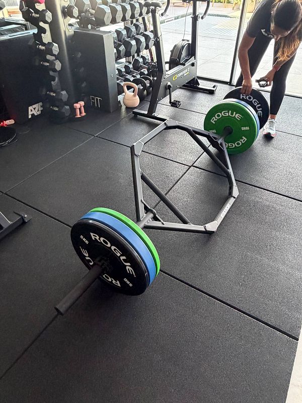 A woman in workout attire is performing a kettlebell exercise in a gym setting.