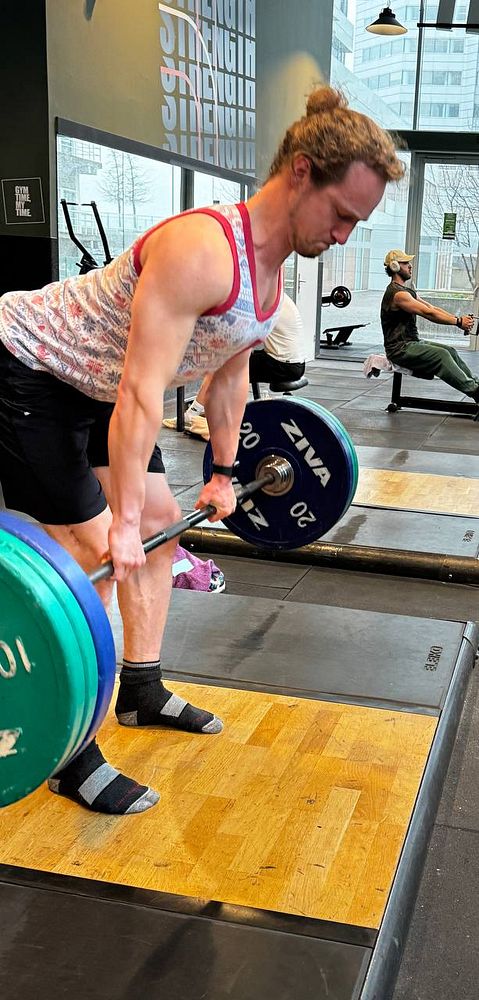 A minimalist architectural interior featuring a tall concrete wall with a strategically placed stairmaster exercise machine in a corner.