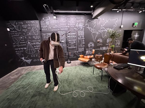A person is playtesting a virtual reality experience in a creatively designed room filled with mathematical diagrams and a cozy seating area.