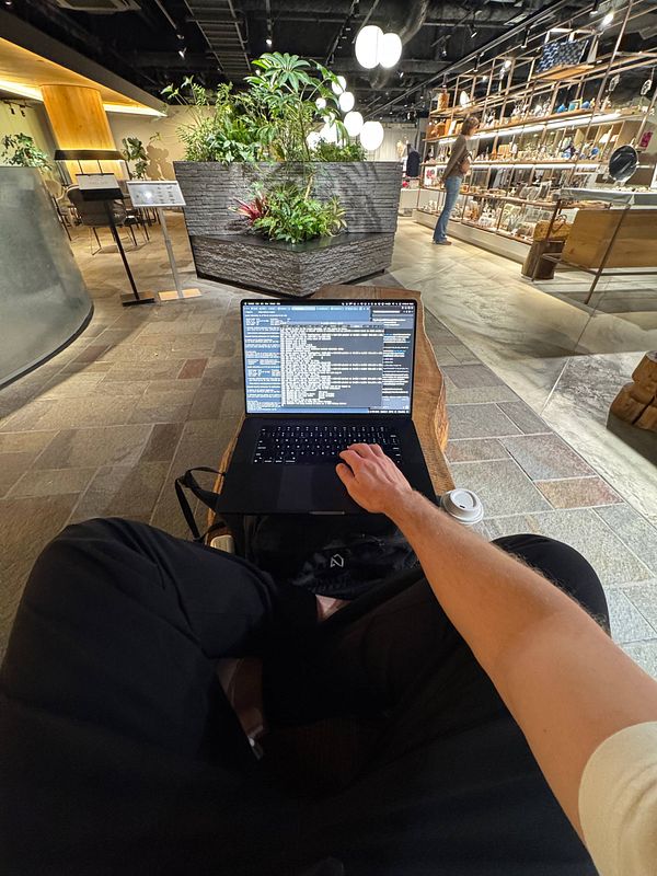 A digital nomad is working on a laptop in a stylish cafe environment.