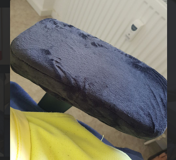 Close-up view of a metal chair frame with an armrest missing its foam padding alongside a roll of new foam cushioning.