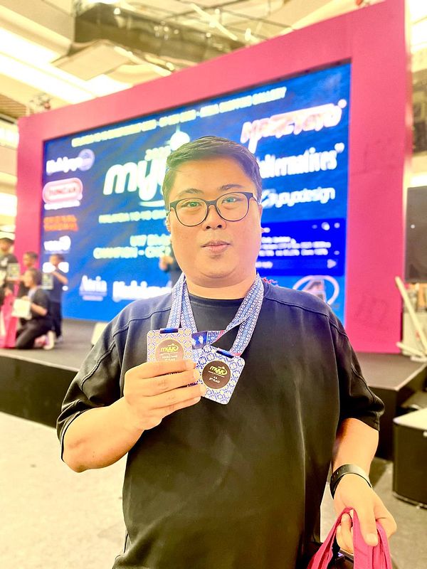 A person proudly displays two medals at an event.