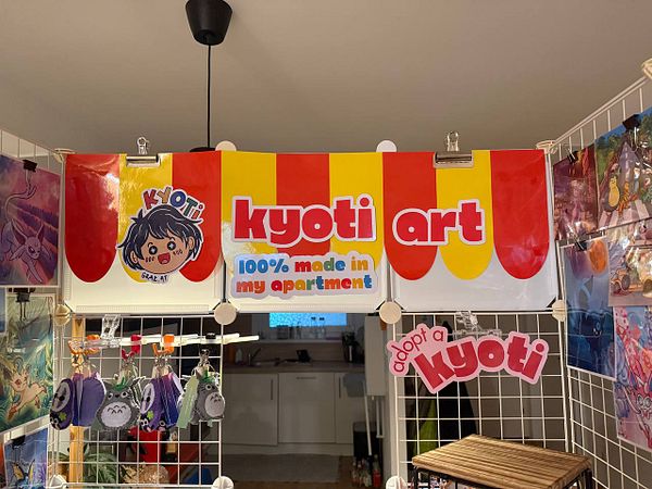A colorful booth display featuring kyoti branding and art products.