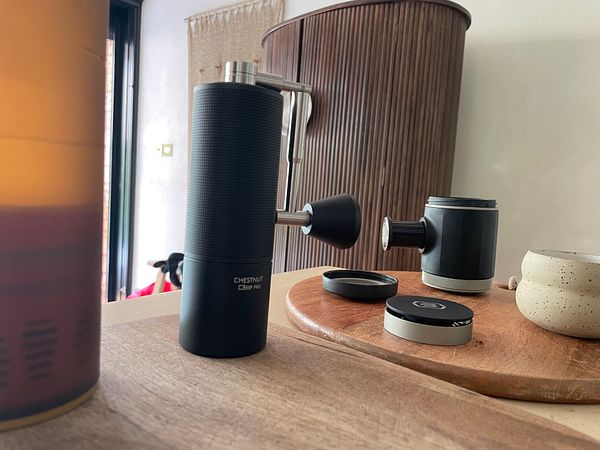 A stylish coffee setup featuring a portable grinder and espresso maker on a wooden surface.