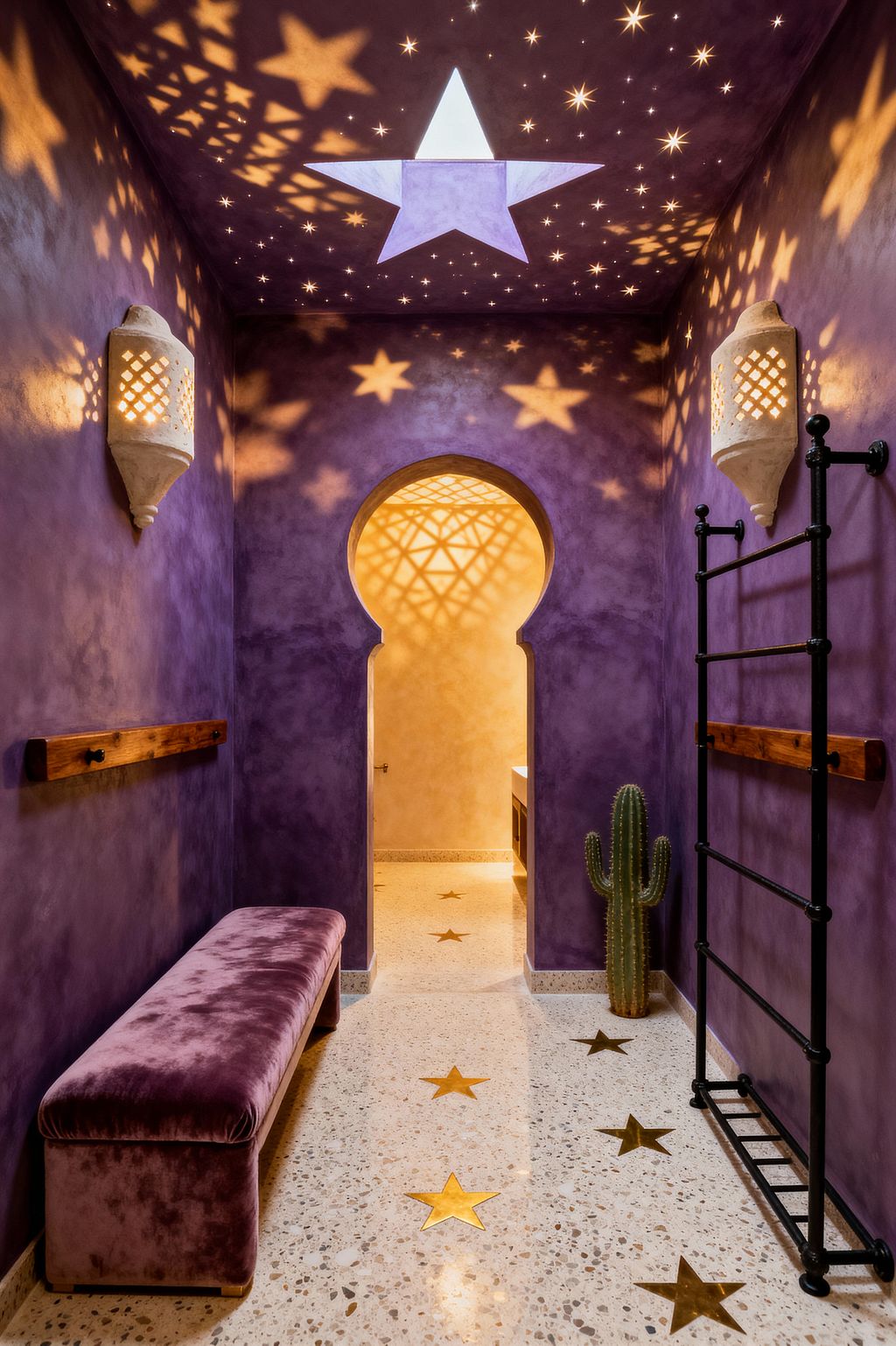 A narrow Moroccan-style home gym with deep violet plaster walls features a starry ceiling and a large star-shaped skylight casting warm patterned light. A terrazzo floor inlaid with brass stars leads to a Moorish keyhole arch, with a mauve velvet bench on the left, a black wrought-iron wall ladder and stained wood rails on the right, white perforated plaster sconces on both sides, and a small cactus near the doorway.