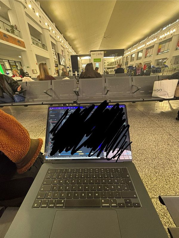 A person is working on a laptop in an airport terminal.