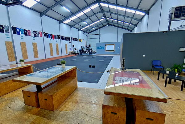 The image depicts a spacious gym area designed for fitness activities, featuring workout equipment and a welcoming seating area.