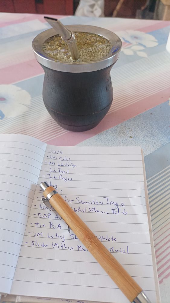 A mate cup and a notebook with a to-do list are placed on a colorful table.