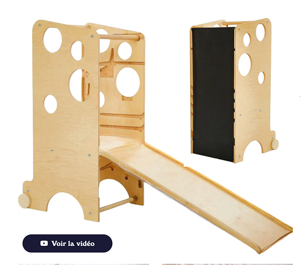 A young girl standing on a Montessori tower step stool helping in the kitchen near a stove with a pot, beside a woman, likely her mother.