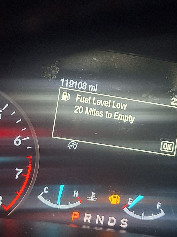 The dashboard display indicates low fuel levels in a vehicle.