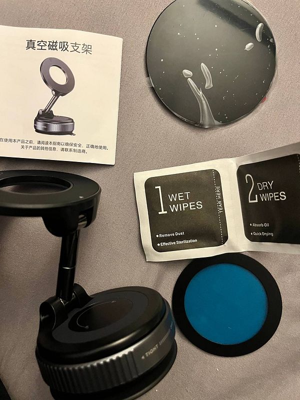 The image displays a phone holder kit with cleaning wipes and an instruction manual.