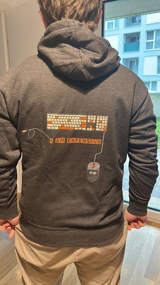 A person is wearing a dark hoodie featuring a humorous design related to freelancing.