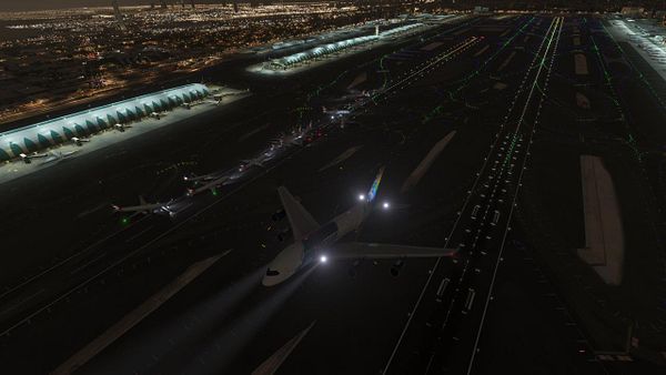 A nighttime aerial view of a busy airport in Dubai, showcasing multiple aircraft on the runway and taxiways.