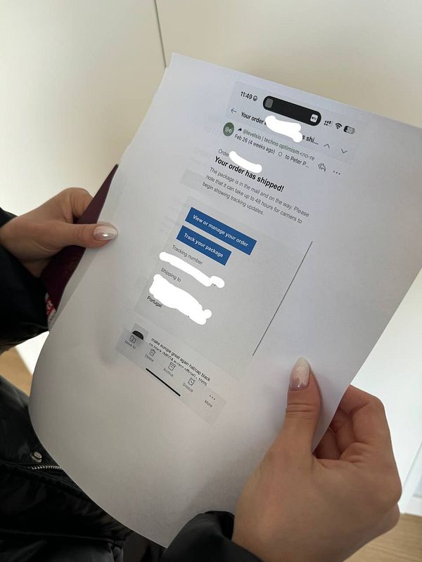 A person is holding a printed screenshot of an order confirmation email from their iPhone.