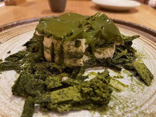 A visually appealing matcha cheesecake is presented on a textured plate.