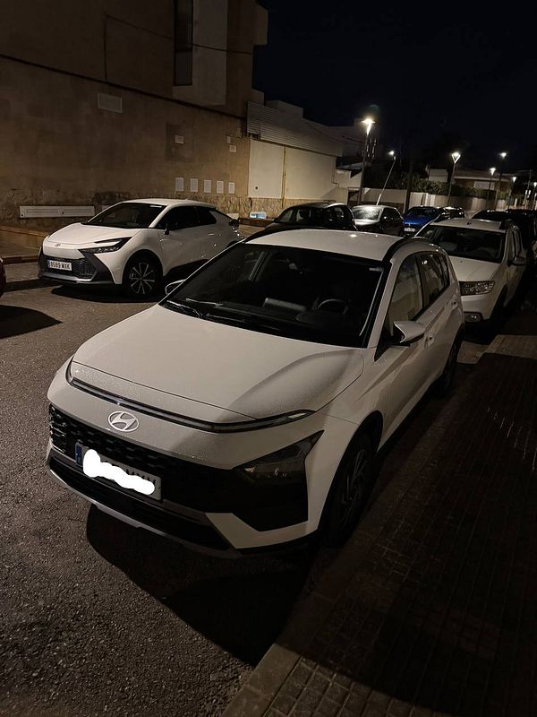 A white Hyundai car parked on a street at night.