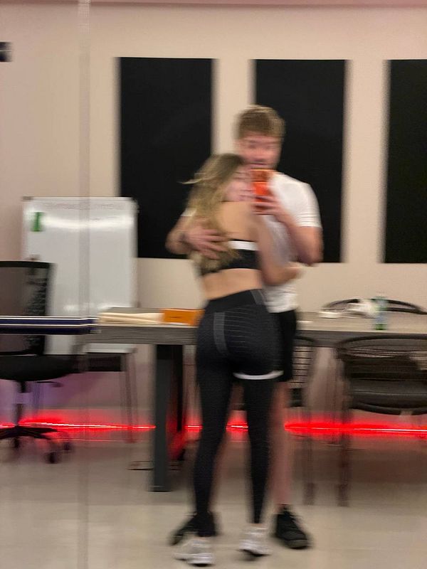 Photograph of a large modern gym interior with multiple exercise machines and gym equipment arranged on green and blue flooring under bright overhead lighting.