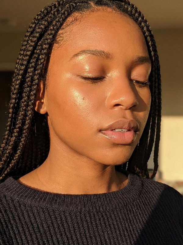 A close-up portrait of a young woman with braided hair, showcasing her natural beauty and glowing skin.