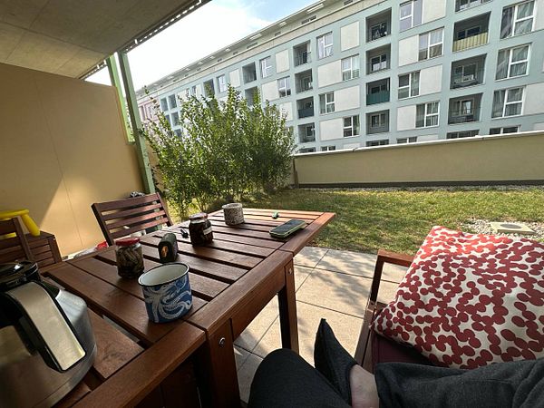 A cozy outdoor seating area with a view of a garden and nearby apartment building.