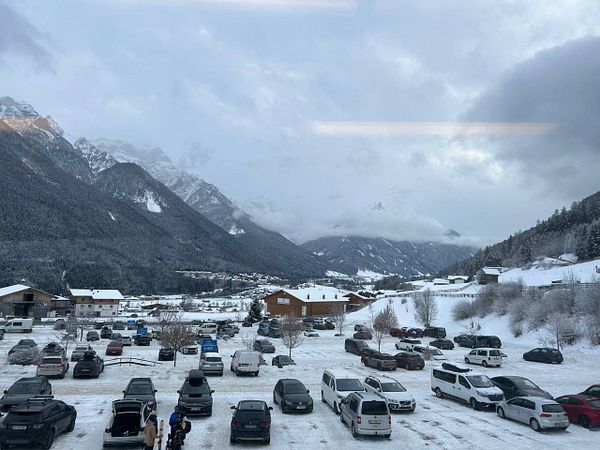 Aerial view of snow-covered mountains with ski tracks and a cloudy blue sky on the final day of skiing.