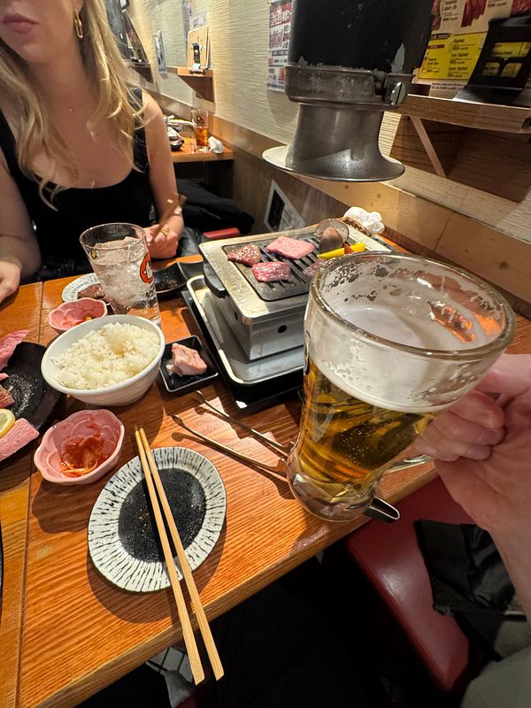 A dining scene featuring grilled wagyu beef, rice, and Sapporo beer in a Tokyo restaurant.