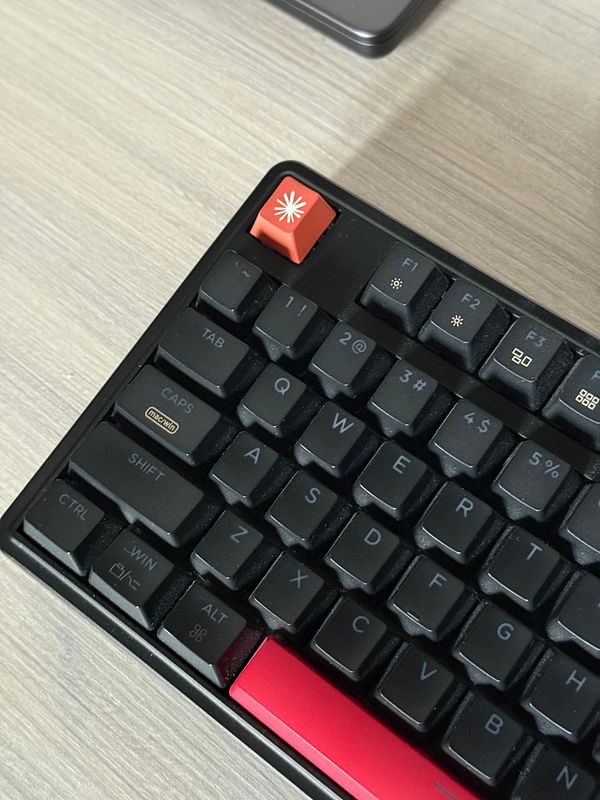 A close-up photo of a mechanical keyboard with a customized keycap labeled 'Claude' installed, surrounded by other keycaps with purple and black colors.