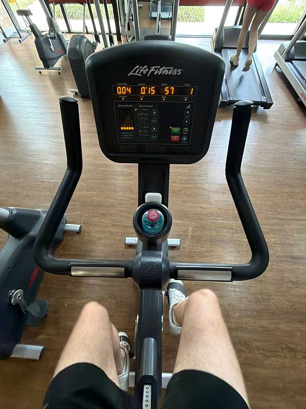 Muscular person lifting dumbbells in a gym with motivational slogan on the wall.