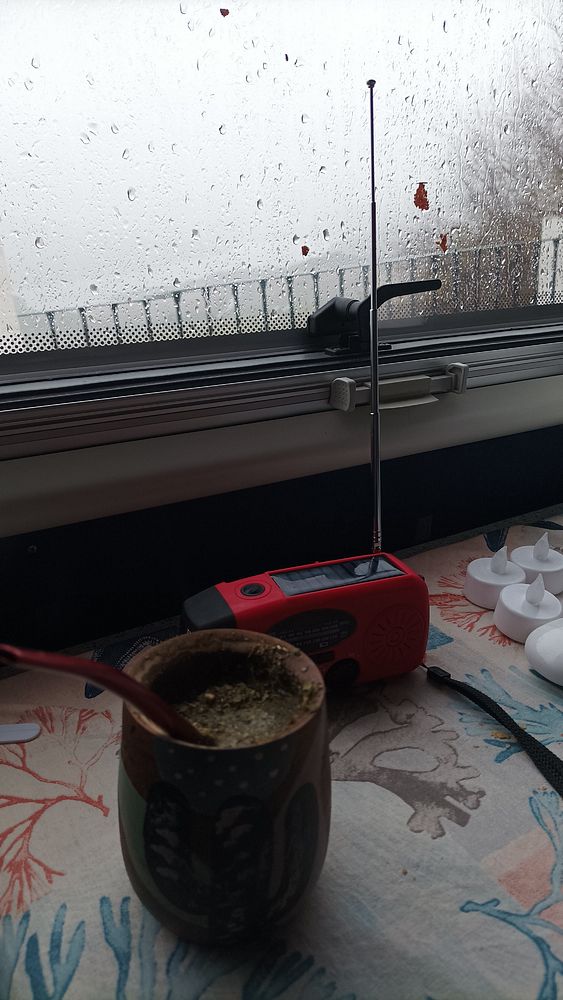 A cozy indoor scene featuring a rainy window, a traditional drink, and a radio.