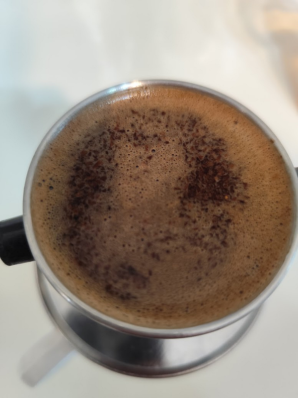 A close-up view of brewed coffee in a traditional phin filter.