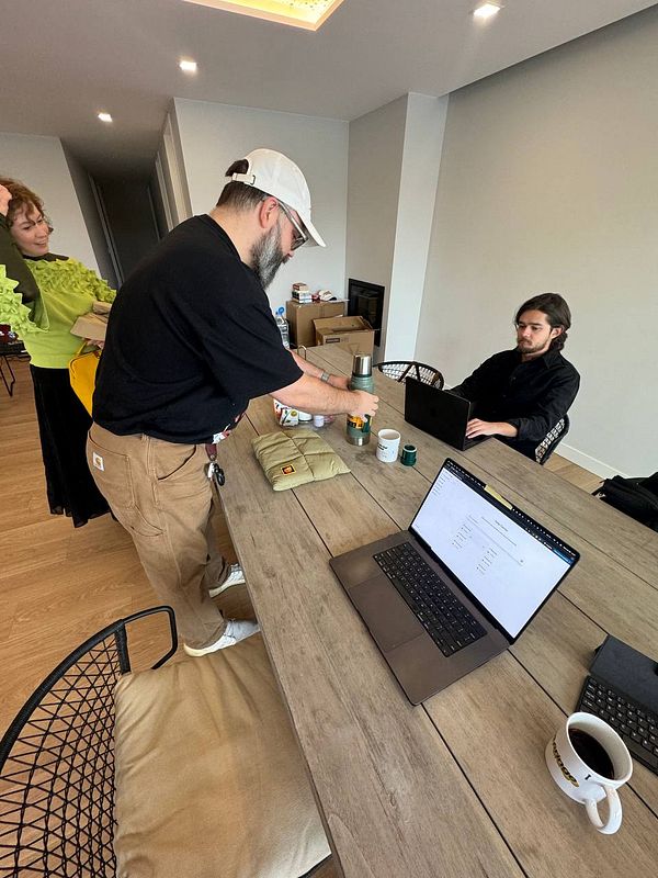 A coworking space is set up with individuals preparing for a collaborative workday.