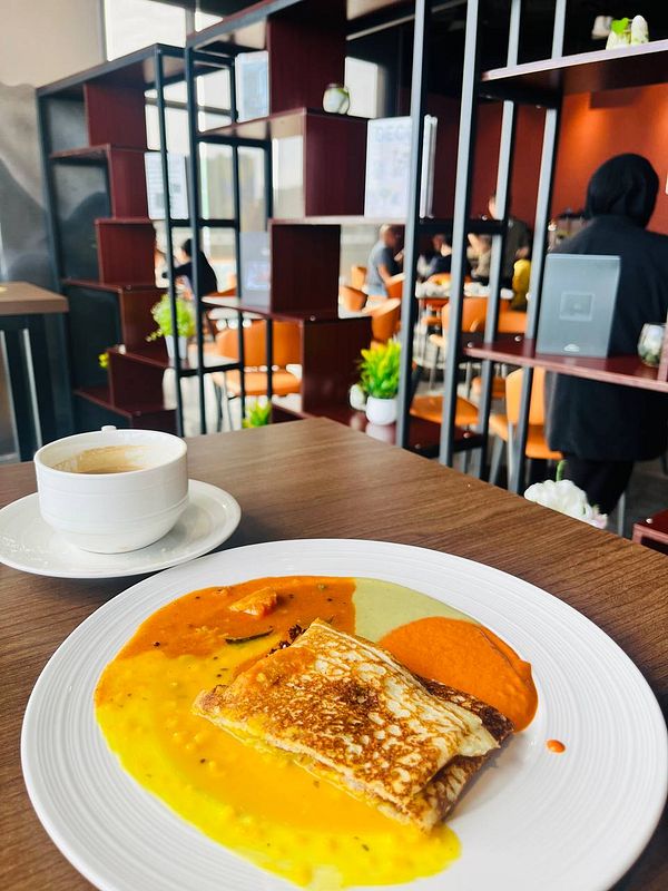 A plate of food featuring tosei and a cup of coffee in a modern café setting.