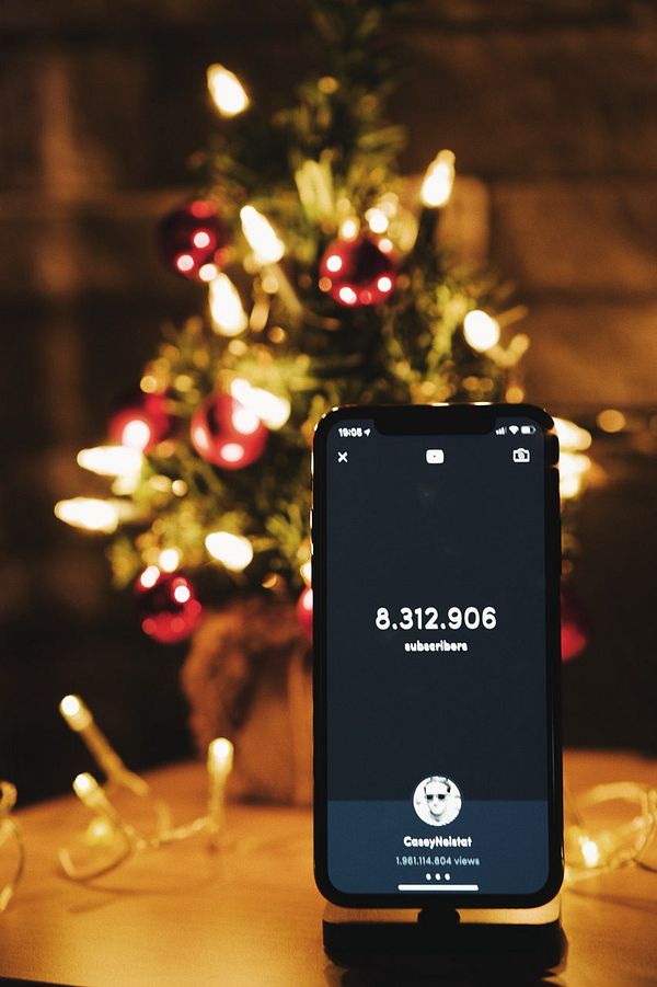 A smartphone displays YouTube subscriber statistics in a festive setting.