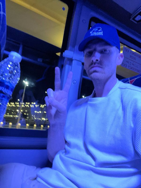 A person is sitting on a bus, making a peace sign with their hand.