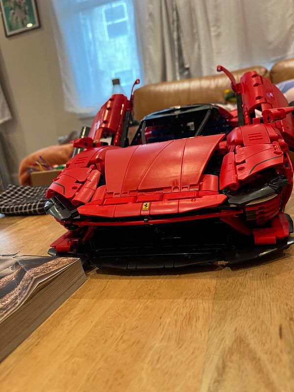 A detailed model of a red Ferrari is displayed on a wooden table.