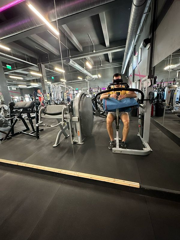 A person is exercising on a gym machine in a modern fitness facility.