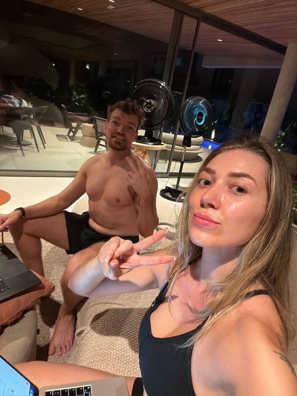 A nighttime cityscape featuring a brightly lit bridge spanning a calm river with city buildings visible in the background under a dark sky.