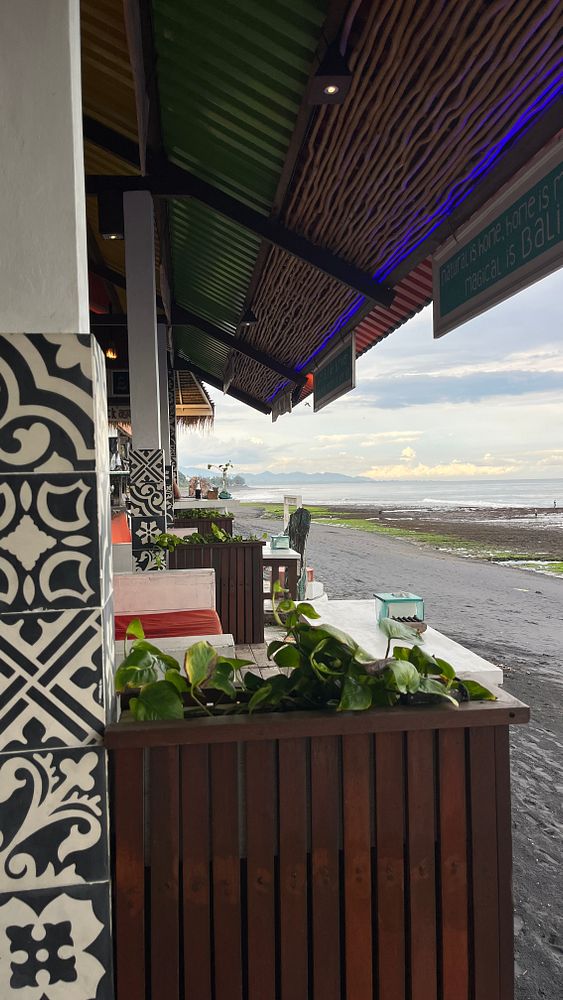 A vibrant outdoor dining area in Bali overlooking a beach.