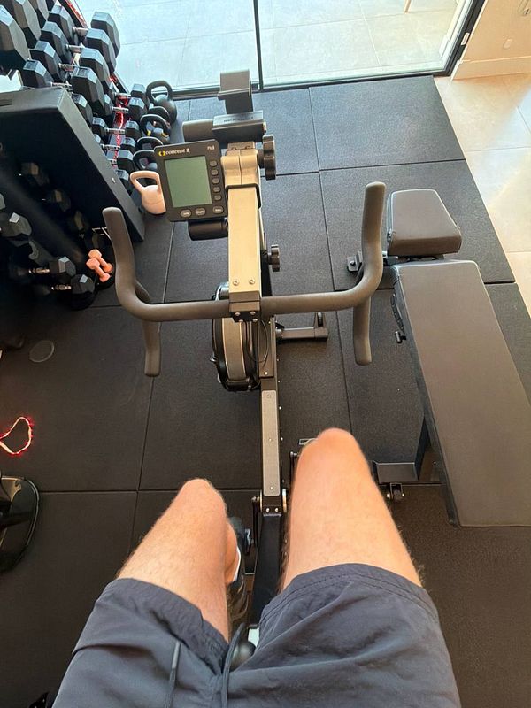 Photo of a gym setting with a person using gym equipment including weights and a squat rack.