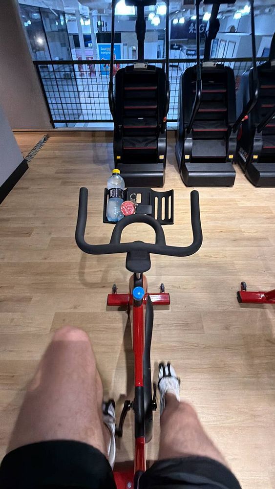 A young man wearing a tank top and shorts is using a weight machine in a gym.