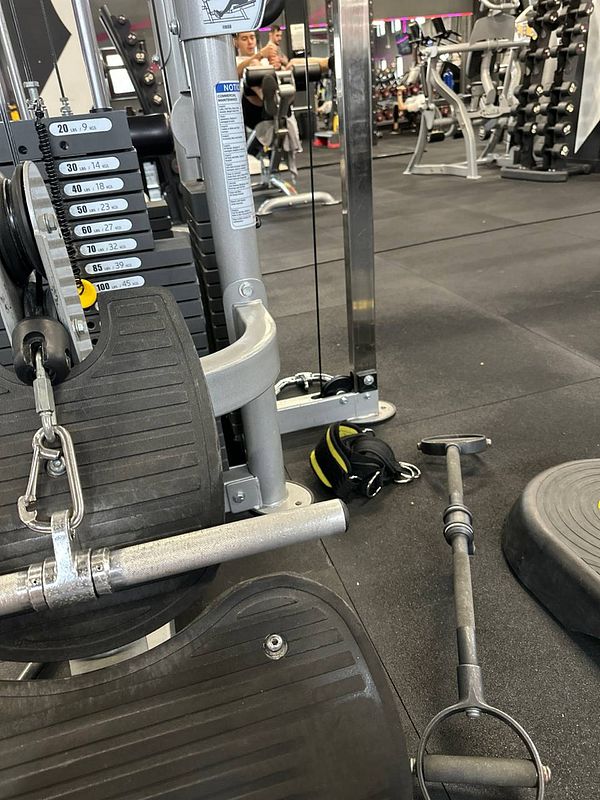 The image captures a gym setting with exercise equipment and weights.