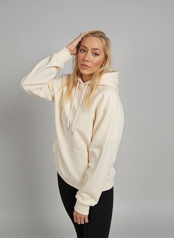 A young woman poses in a light-colored hoodie against a neutral background.