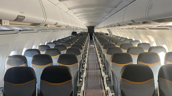 The image depicts the interior of an airplane cabin with rows of seats.