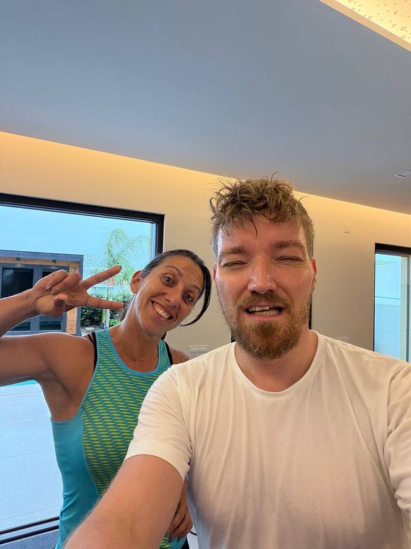 A photograph of a woman performing a barbell squat in a gym setting.