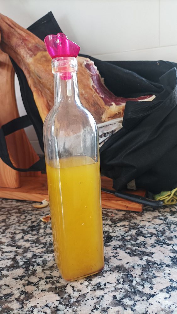 A bottle of homemade olive oil is prominently displayed on a kitchen countertop.