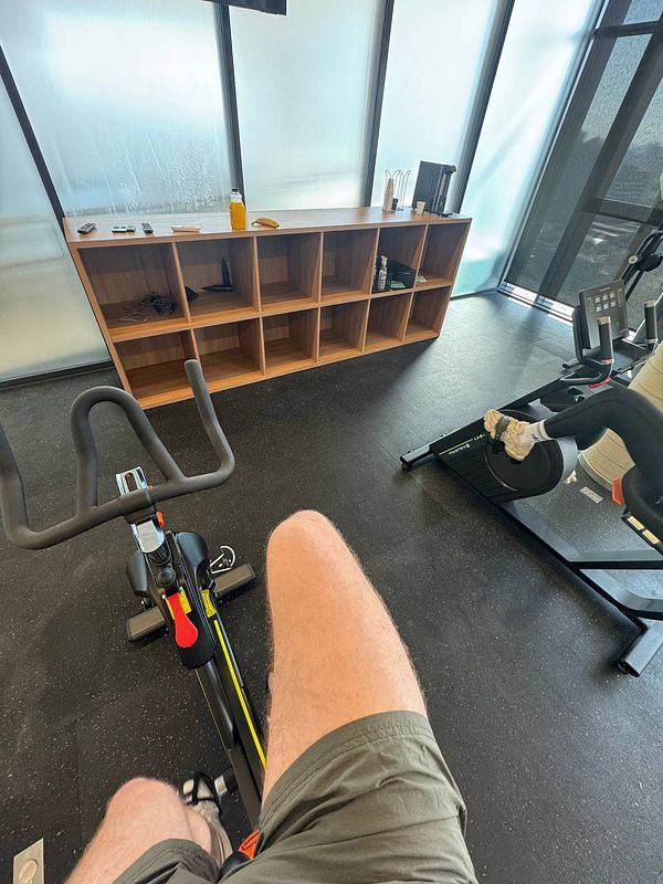 A person is seated on an exercise bike in a gym setting.