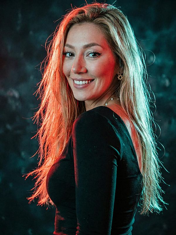 A photorealistic digital portrait of a woman with short hair in a green plaid shirt, set against a dark textured background.