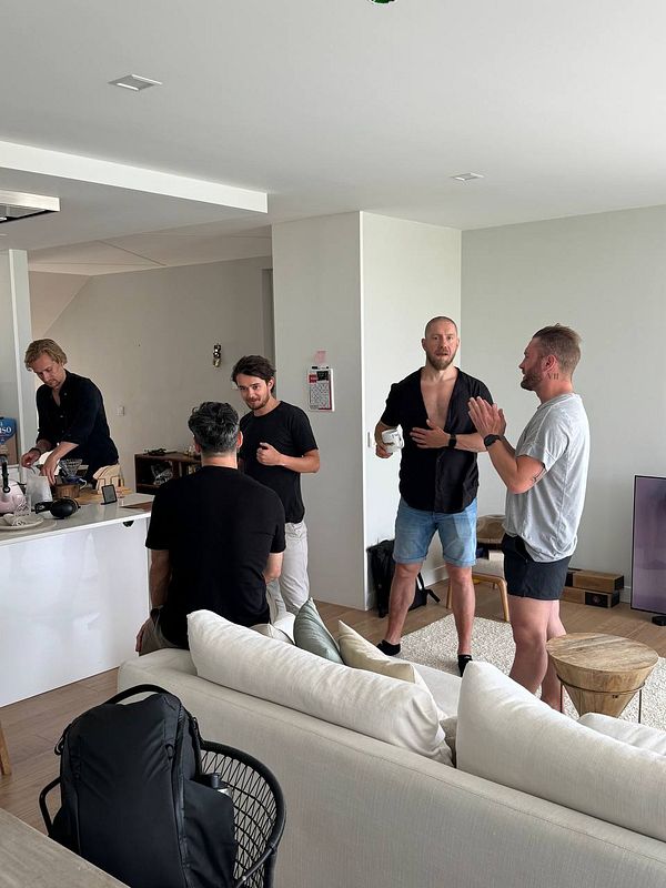 A group of four men are engaged in conversation in a modern living space.