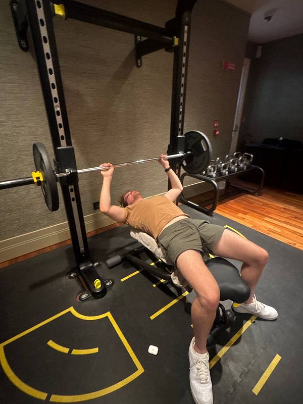 A person is performing a bench press exercise in a gym setting.