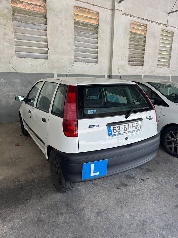 A white Fiat car parked in a garage with a learner's plate displayed.